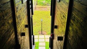 Una scala in legno conduce a un balcone che si affaccia su un campo verde e una casa all'orizzonte.