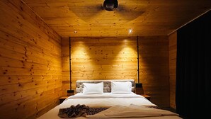 Una camera da letto con soffitto in legno, un letto con biancheria bianca e un comodino.