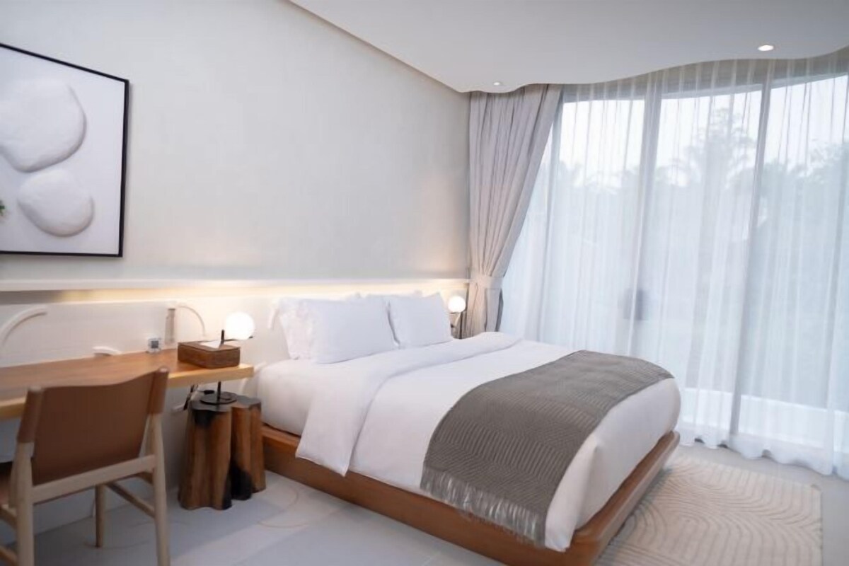 Une chambre moderne avec un grand lit, un bureau et une chaise.