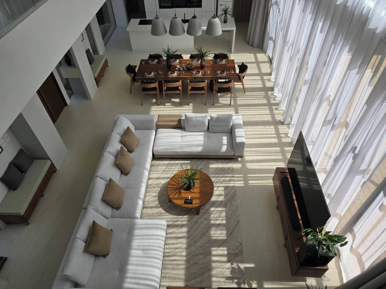 A spacious living area with a large sofa set, a dining table with chairs, and a coffee table.