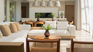 Un salon moderne avec un canapé blanc, une table basse ronde en bois et une plante en pot.