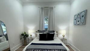 A bedroom with a bed, bedside tables, a ceiling fan, and a window with curtains.