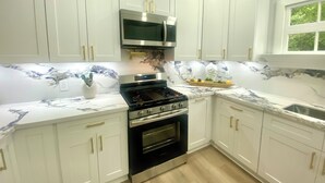 A modern kitchen with white cabinets, a stainless steel stove, and a microwave.
