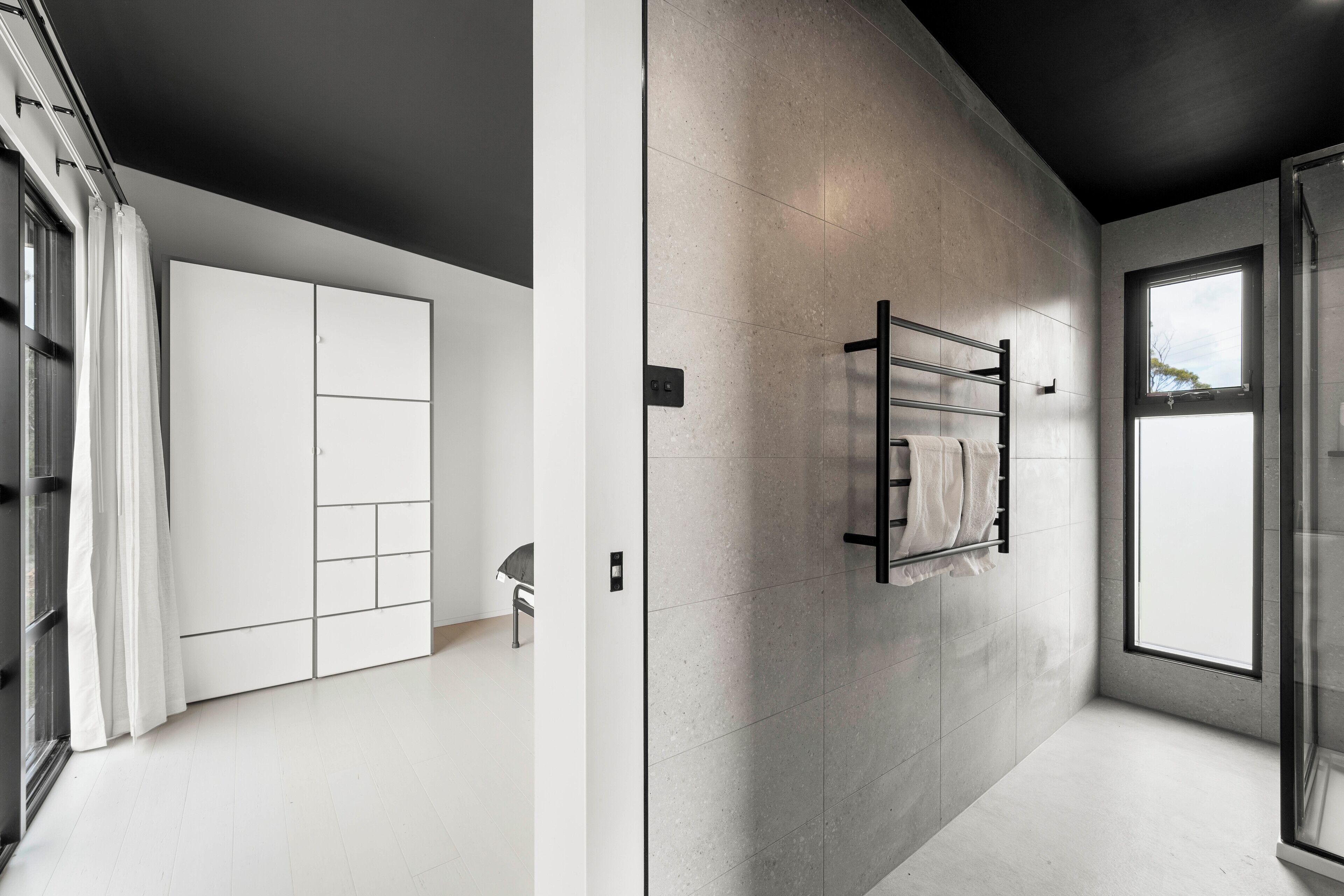 A modern bathroom with a large mirror, a towel rack, and a window providing natural light.