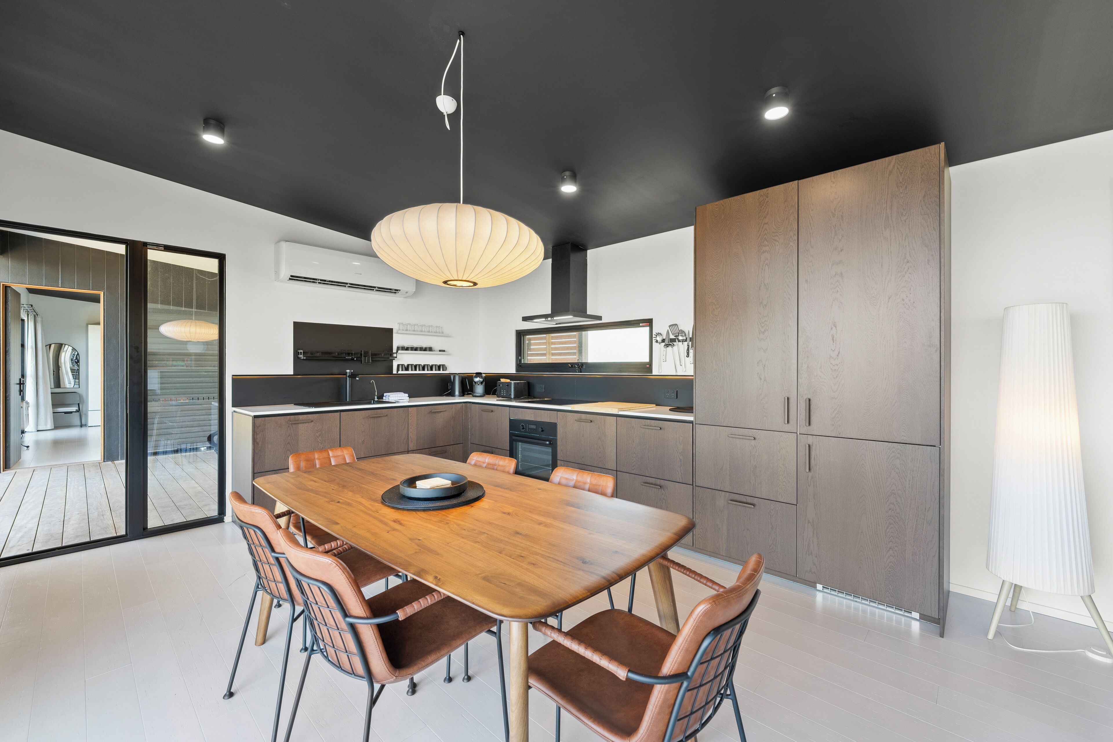 A modern kitchen with a wooden dining table, built-in appliances, and a large cabinet.