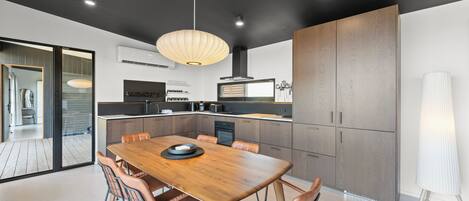 A modern kitchen with a wooden dining table, built-in appliances, and a large cabinet.