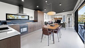 Una cocina moderna con comedor, que cuenta con una isla grande, electrodomésticos integrados y vistas al exterior.
