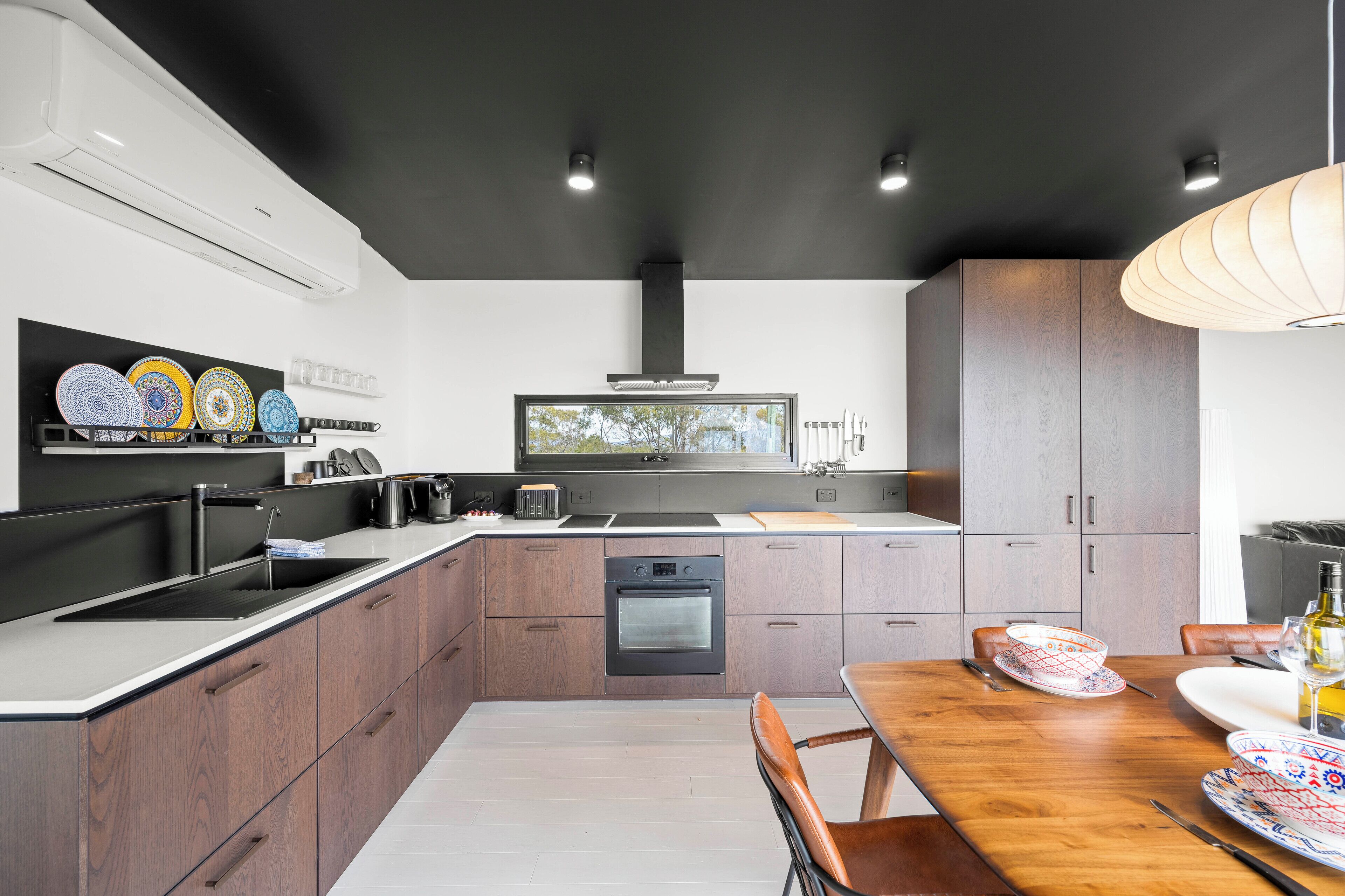 Una cocina moderna con una isla central, electrodomésticos integrados y un comedor con mesa y sillas de madera.