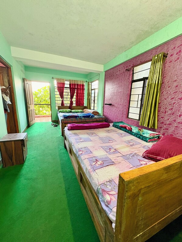 A room with three wooden beds, green carpet, and a view of greenery outside. - Golden Sunview Homesay (Kurseong)