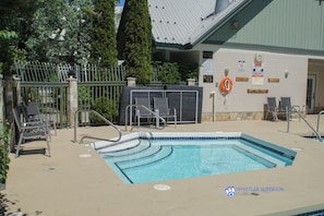 Ein Schwimmbecken mit Rettungsboje, Liegestühlen und einem überdachten Bereich mit Sitzgelegenheiten.