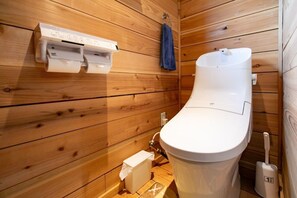 A compact wooden cabin bathroom with a toilet, a bidet, and a hand dryer. - A log house with a 100% natural hot spring. (Usu Gun Sobetsu Cho)