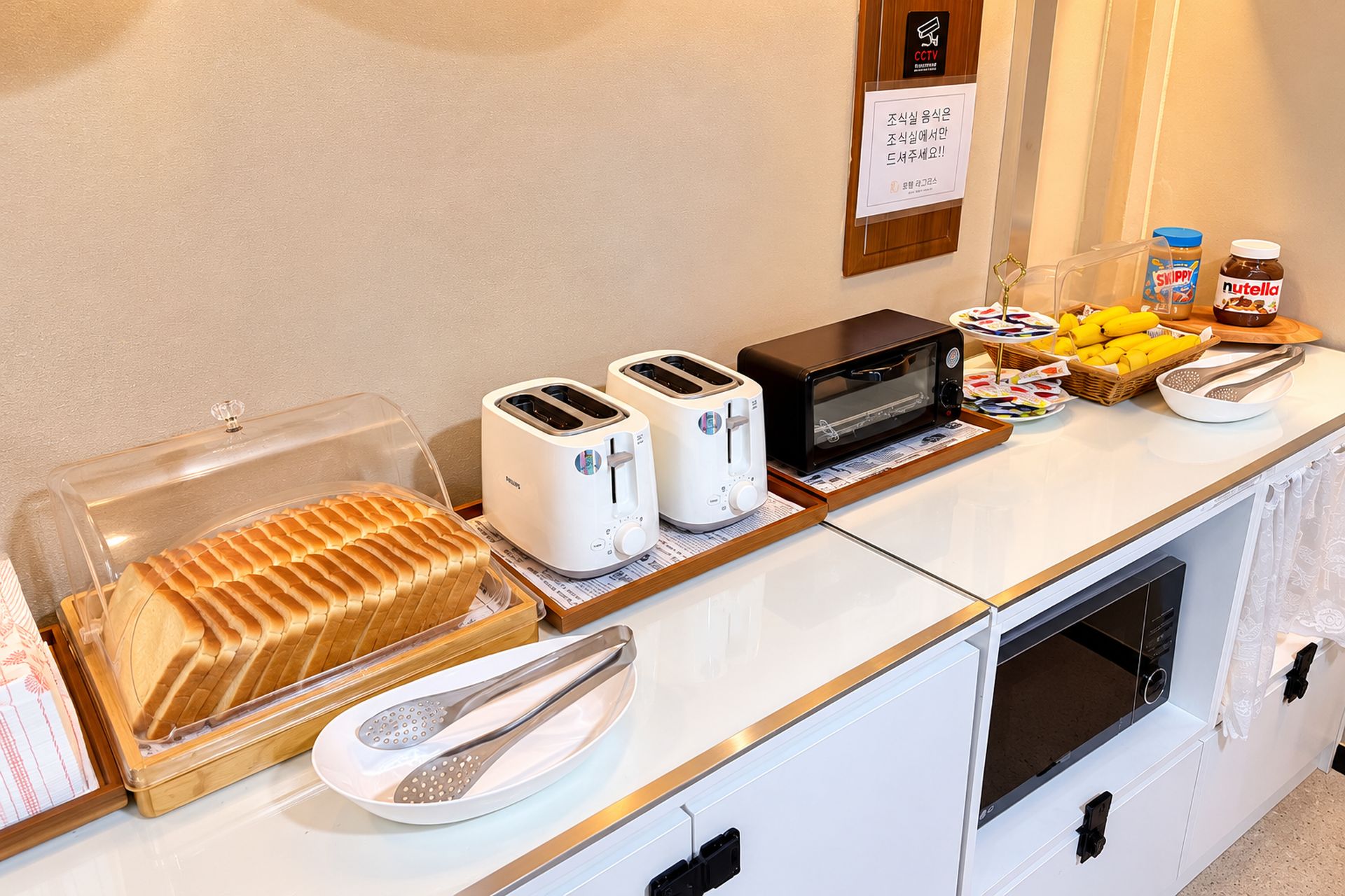 Montaje de un bufé de desayuno con tostadoras, un microondas y diversos alimentos.