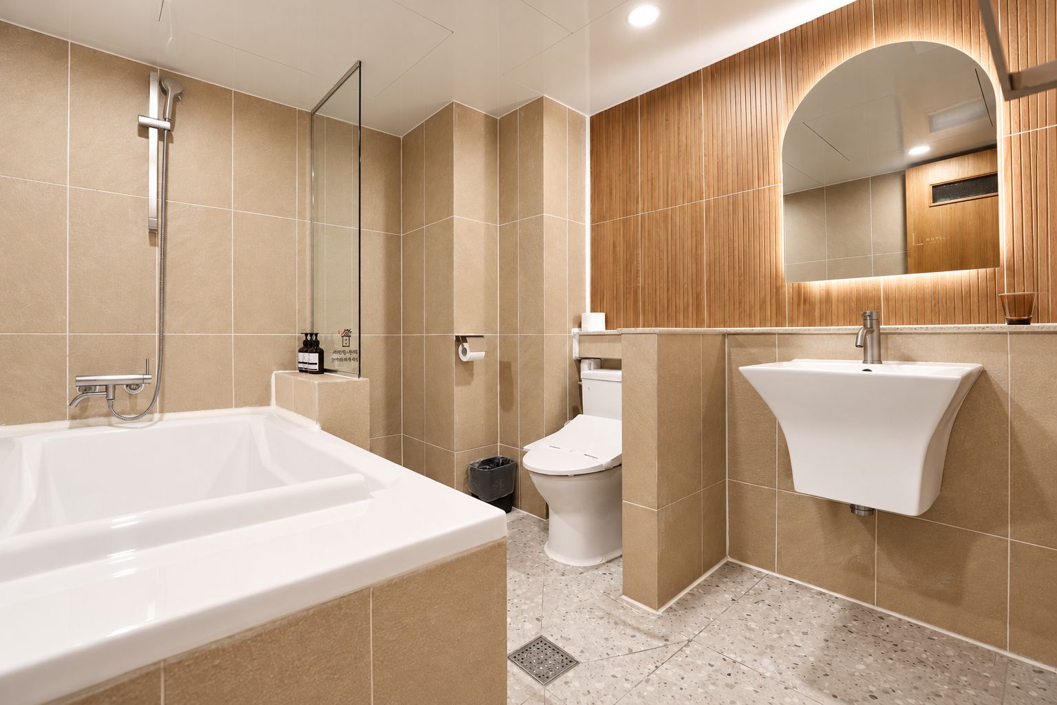 A modern bathroom with a bathtub, toilet, and sink, featuring wooden paneling and a large mirror.