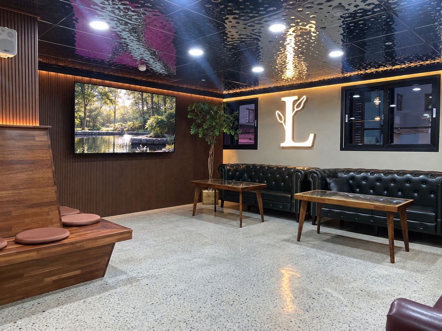 A modern interior with a reception desk, seating area, and a large TV screen displaying a nature scene.