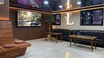 Ein modernes Interieur mit einer Rezeption, einer Sitzecke und einem großen Fernseher, der eine Naturlandschaft zeigt.