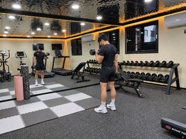 Un gimnasio con equipo de ejercicio, un espejo y una pared con temática de Star Trek.