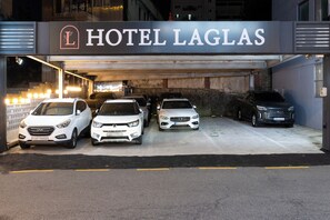 Entrada de hotel con un cartel que dice 'HOTEL LAGLAS' y varios coches estacionados.