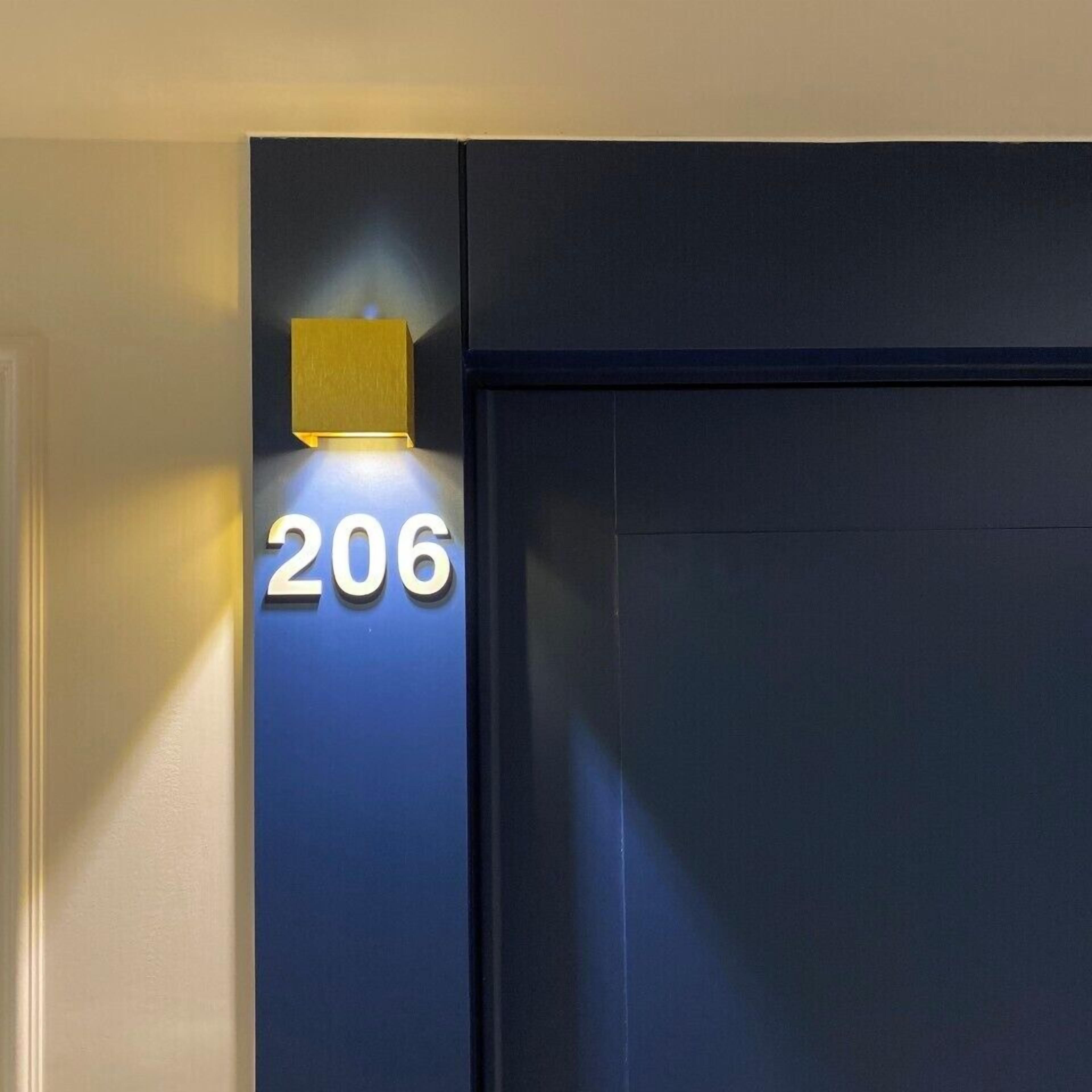 Fachada de edificio con el número '206' iluminado en blanco.