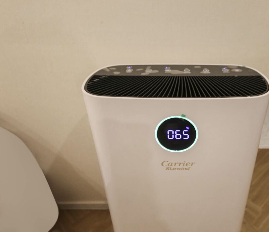 A white Carrier KlearWind air purifier with a digital display showing 065.