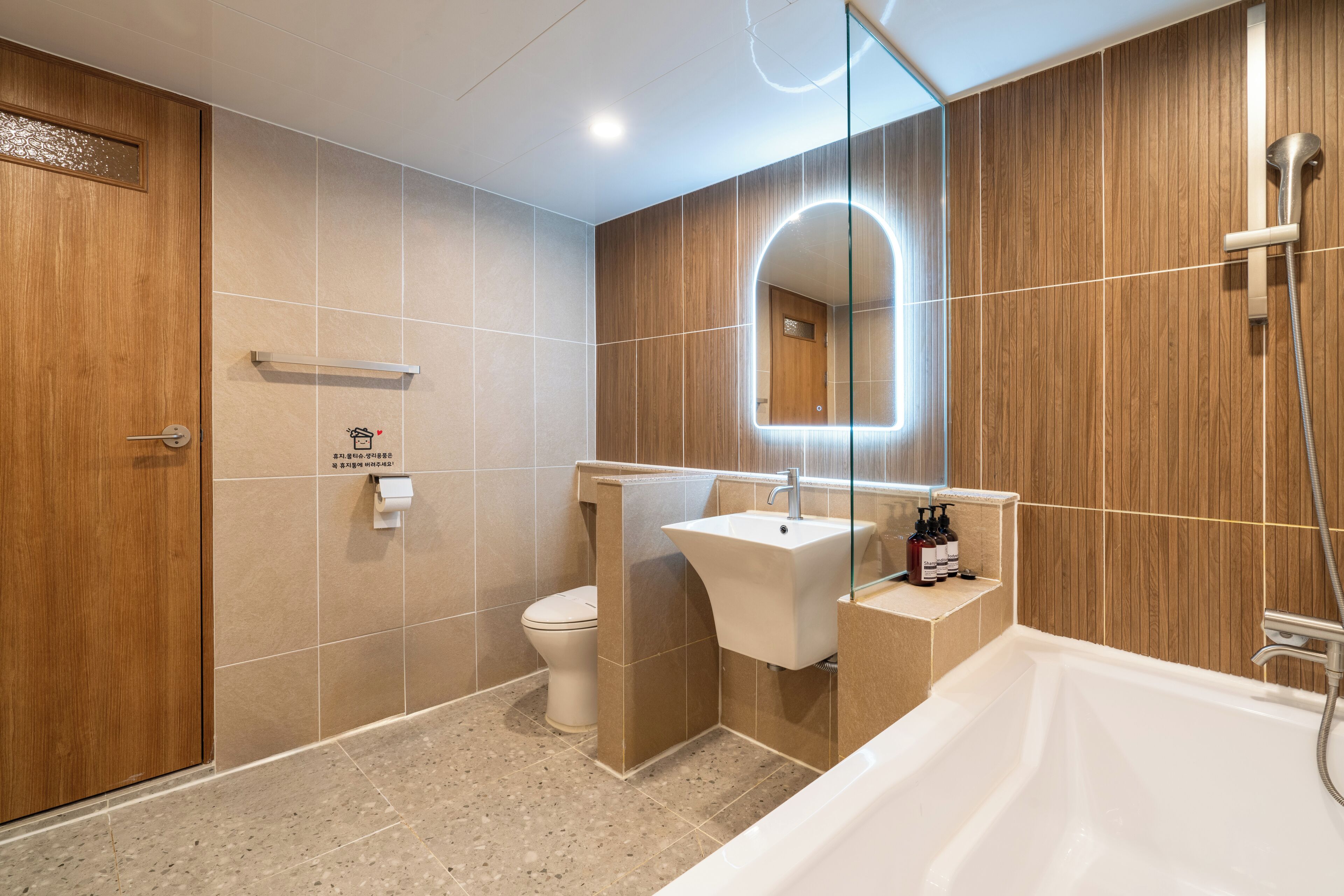 Ein modernes Badezimmer mit einem Holzbadschrank, einem Waschbecken, einer Toilette und einer Badewanne.