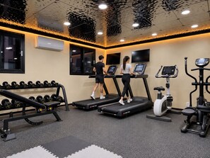 Un gimnasio con cintas de correr, pesas y equipamiento de ejercicio.