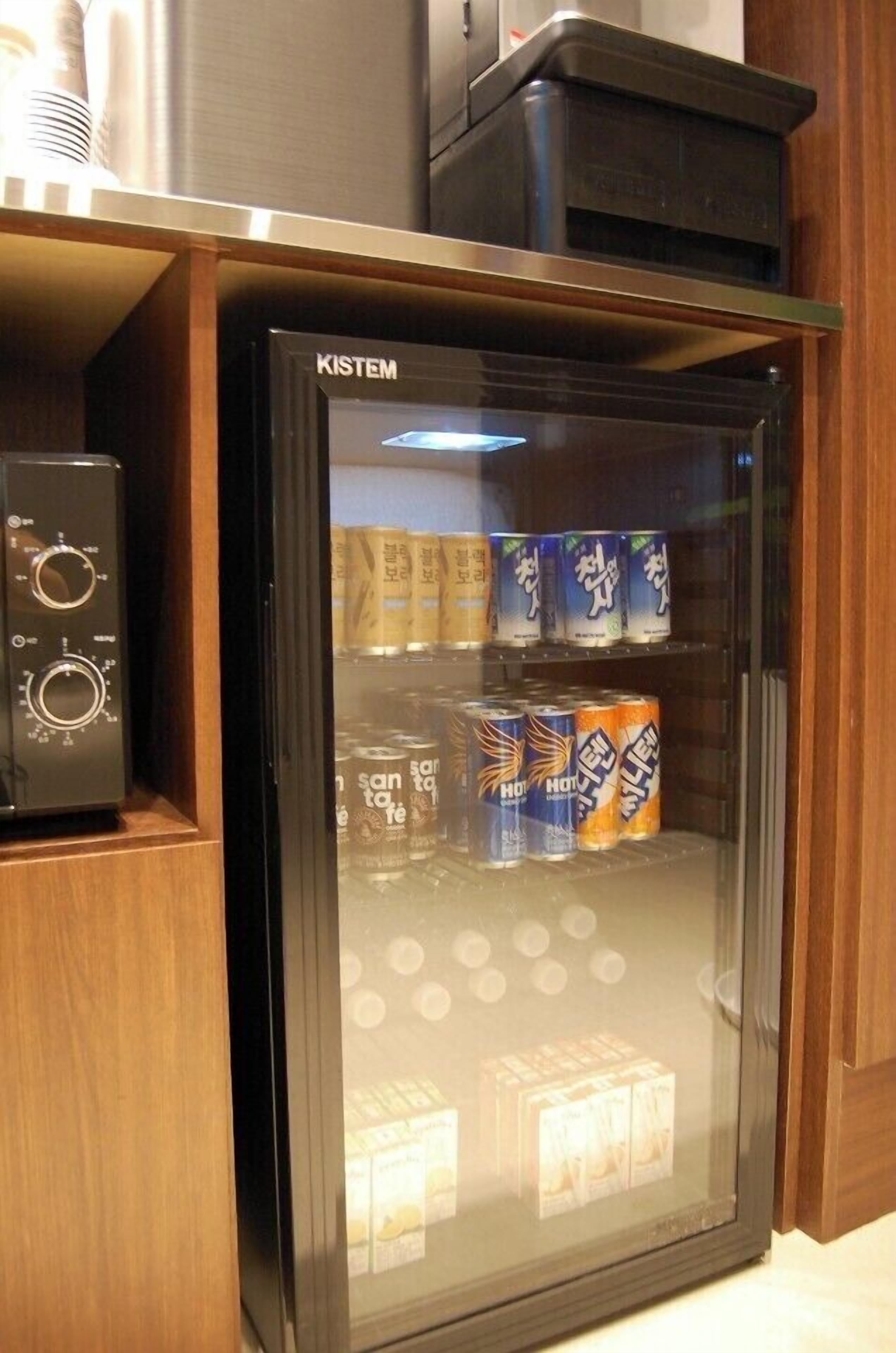 Un minibar con un frigorifero KISTEM, contenente bevande e snack.
