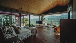 Un dormitorio espacioso con una cama grande, televisor y vistas a las montañas.