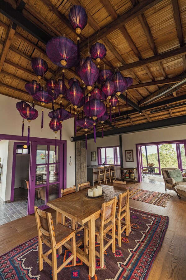 A spacious room with a wooden ceiling, a large dining table with chairs, and purple accents on the walls and ceiling.
