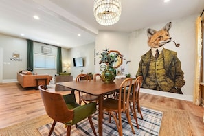 A dining area with a wooden table, chairs, and a large mural of a fox on the wall.