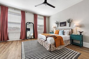 A bedroom with a bed, a nightstand, a mirror, and a ceiling fan.