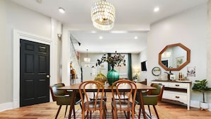 A dining area with a wooden table and chairs, a chandelier, and a mirror on the wall. - ★ HostWise Stays ★ Foxy home, off-street parking, new remodel! (Pittsburgh)