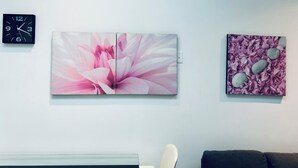 A wall with a clock, a large floral painting, and a smaller artwork.
