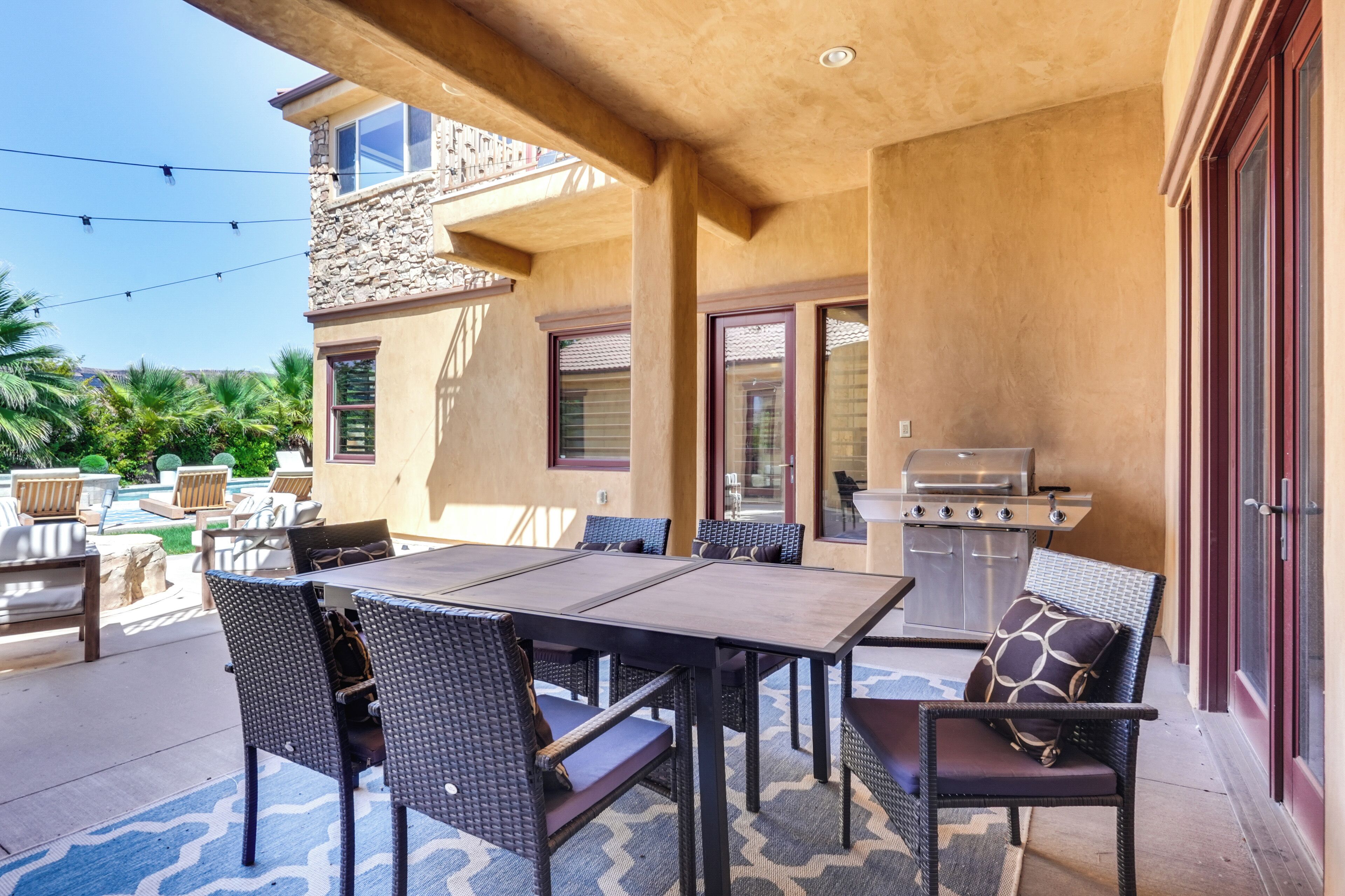 Eine Terrasse im Freien mit Esstisch, Stühlen und Grill.
