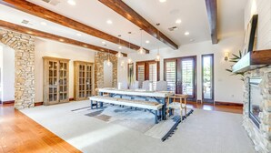 A spacious room with a stone fireplace, wooden beams, and a large dining table with benches. - Washington Villa 1 Mi to Golf: Great for Groups! (Washington)