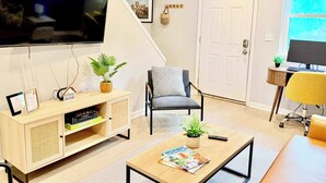 A living room with a television, a bookshelf, a coffee table, and a chair. - The Cobbler 's Abode (Columbus)