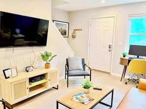 Un salon comprenant un téléviseur, une bibliothèque, une table basse et un fauteuil.