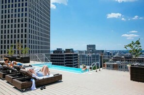Un espace piscine aménagé sur le toit, avec des chaises longues et une vue sur le panorama urbain.