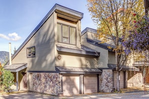 A two-story house with a stone foundation, a garage, and a large window.