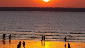A sunset over a body of water with silhouettes of people on the shore. - Zen Bridgeport Waterfront Balcony Dining - Pool (Darwin)