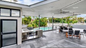 An outdoor patio area with a pool, seating, and a grill. - Downtown Delight 2BR Getaway Pool (Darwin)