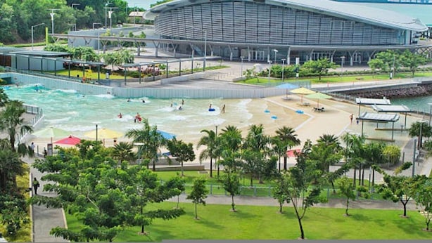 A waterfront hotel with a large swimming pool, a beach area, and a modern building with a curved roof. - Downtown Delight 2BR Getaway Pool (Darwin)
