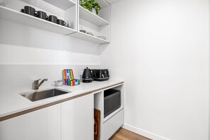A compact kitchen with a sink, a coffee maker, and a microwave.