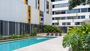 A modern building with a swimming pool, outdoor seating, and lush greenery. - Chic 1 Bed Inner-City Retreat with Pool and Views (Fortitude Valley)
