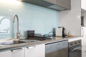 Una cocina moderna con un lavamanos de acero inoxidable, lavavajillas, horno y cafetera.