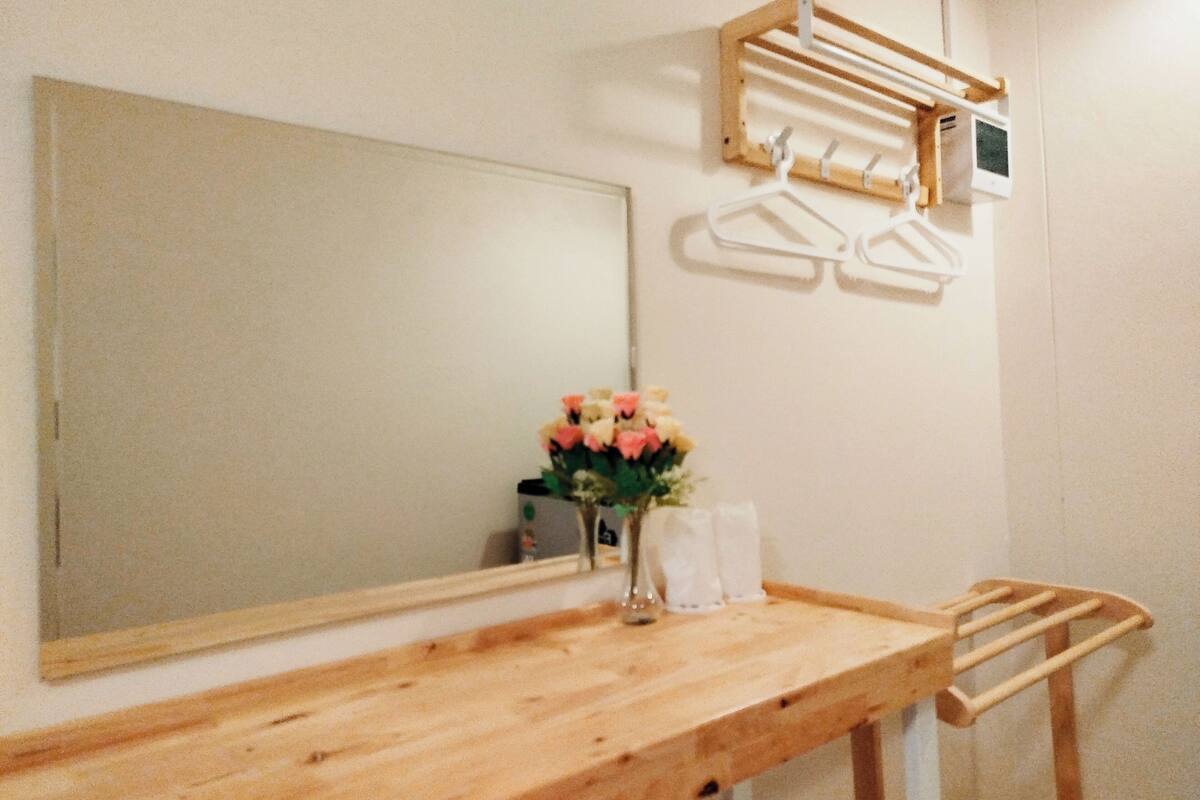 Une salle de bain avec un meuble-lavabo en bois, un miroir, un porte-serviettes et un vase avec des fleurs.