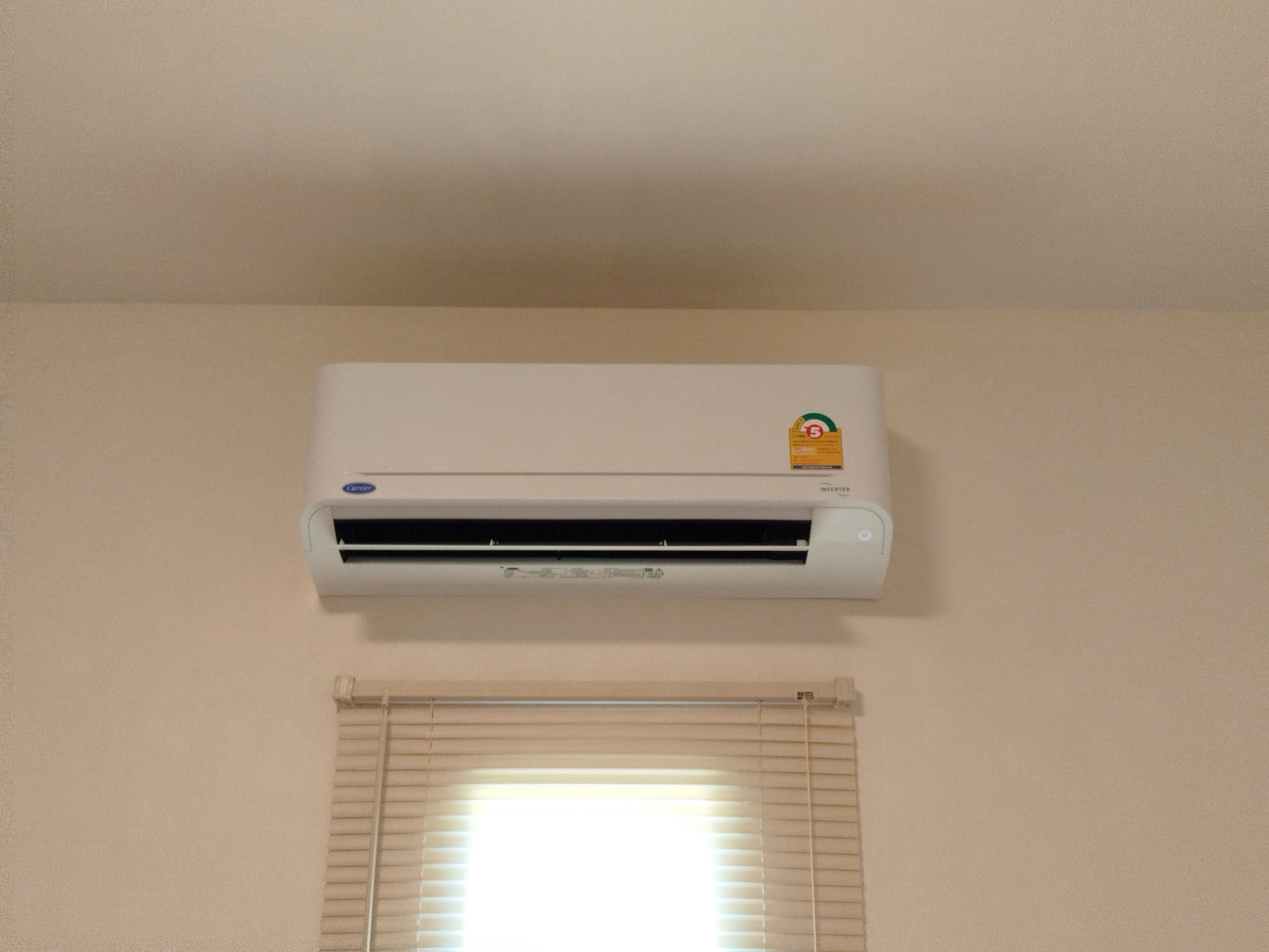 Un aire acondicionado blanco, fijado a la pared, con el logo de la marca visible y una etiqueta que indica tecnología inverter.