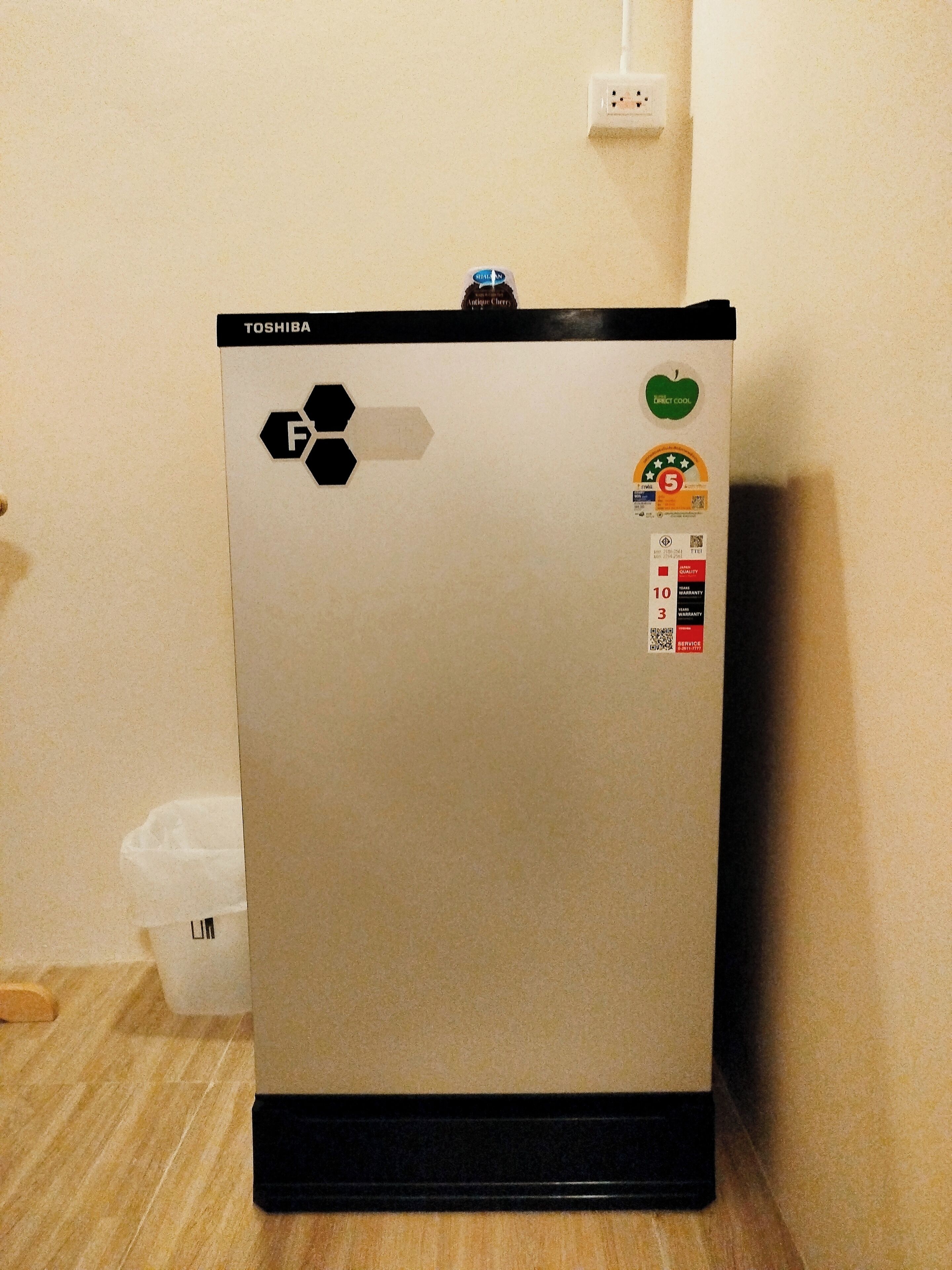 Uma geladeira Toshiba com base preta, visor digital e compartimento de freezer.