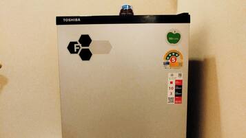 Uma geladeira Toshiba com base preta, visor digital e compartimento de freezer.