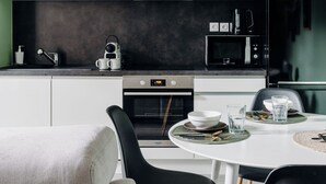 A modern kitchen with a dining area, featuring a white table, black chairs, and a green accent wall with the word "CUISINE".