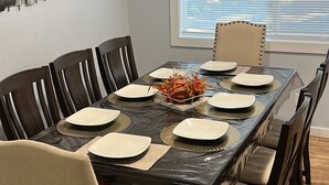 A dining room with a rectangular table set for six, surrounded by dark wooden chairs with light-colored cushions. - The Creek House Spacious 4-bedroom house in brilliant Vancouver with WiFi (Vancouver)